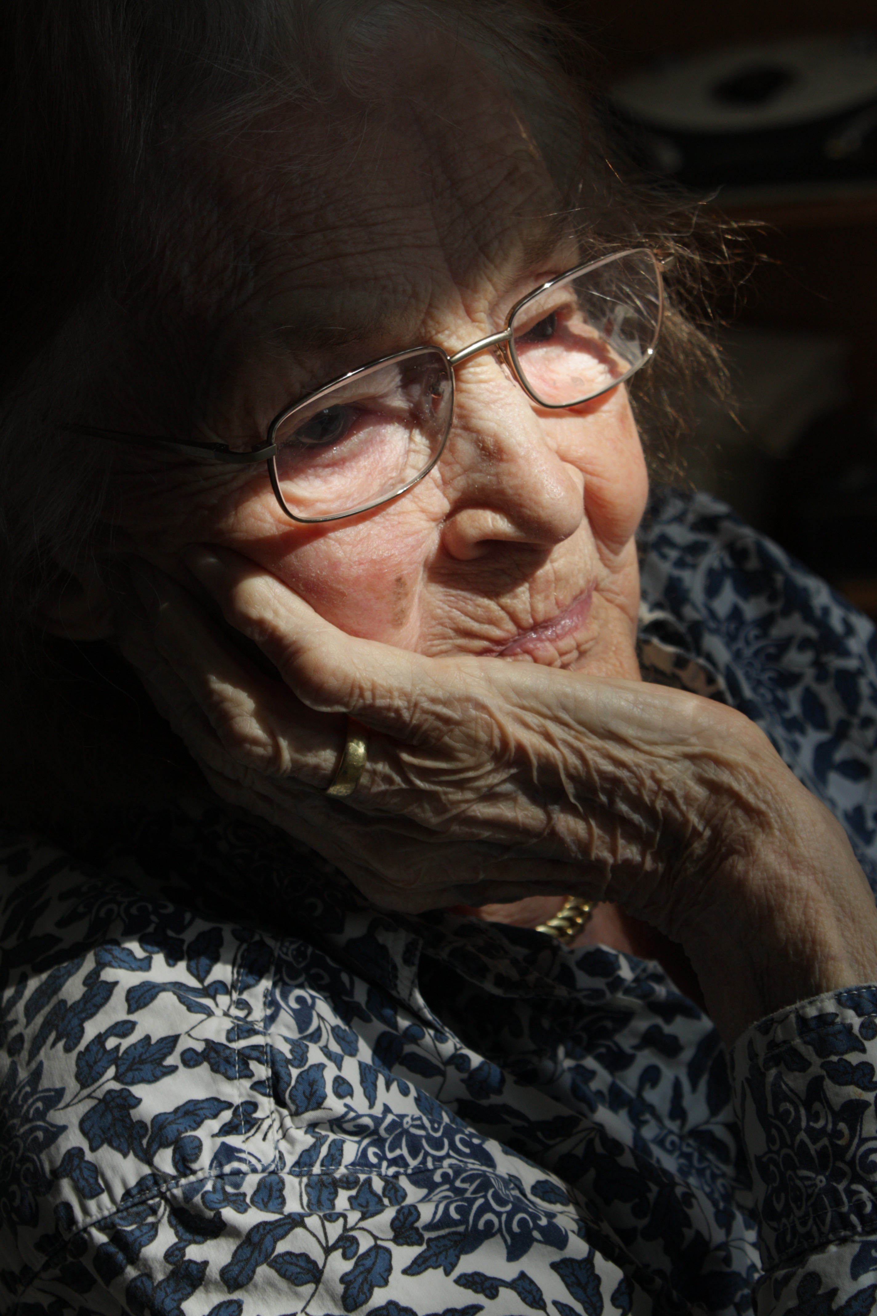 Elderly woman sitting in a ray of light.